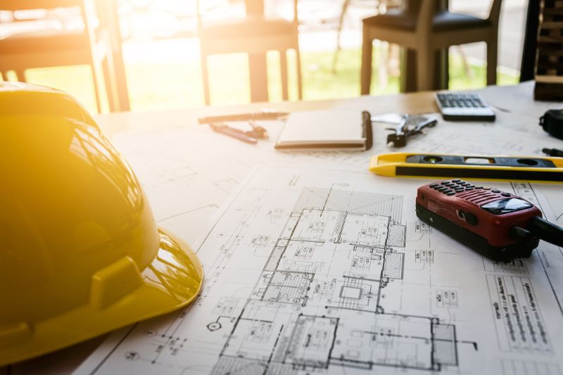 quantity-surveyor-shiny-yellow-helmet-on-plans-min